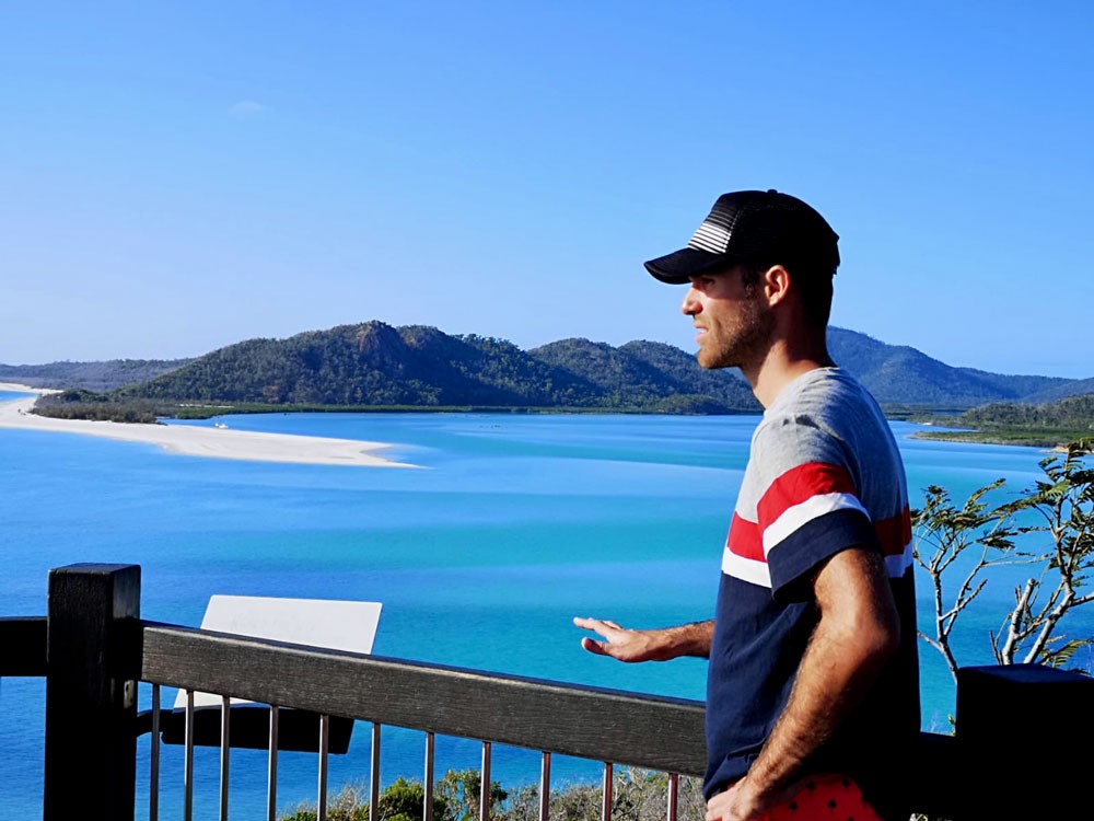 chico moreno con una gorra y detrás el mar y unas montañas